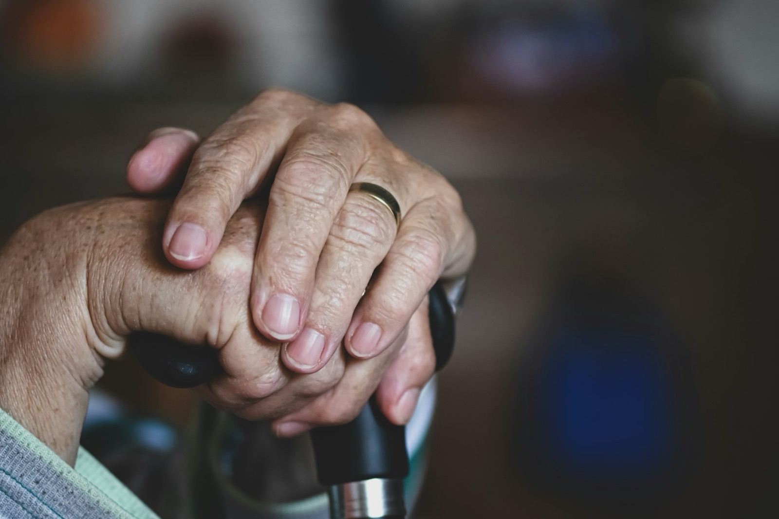 Mãos de uma pessoa idosa apoiadas na bengala